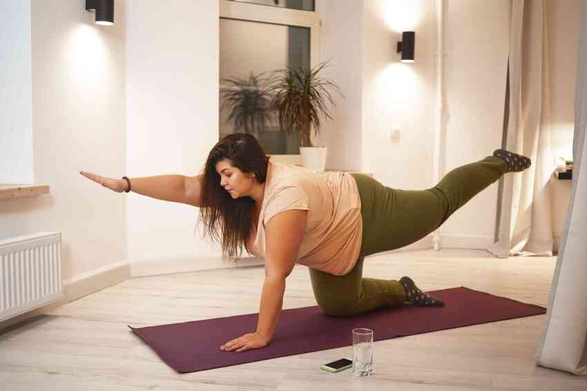 Obézní žena cvičí na podložce.